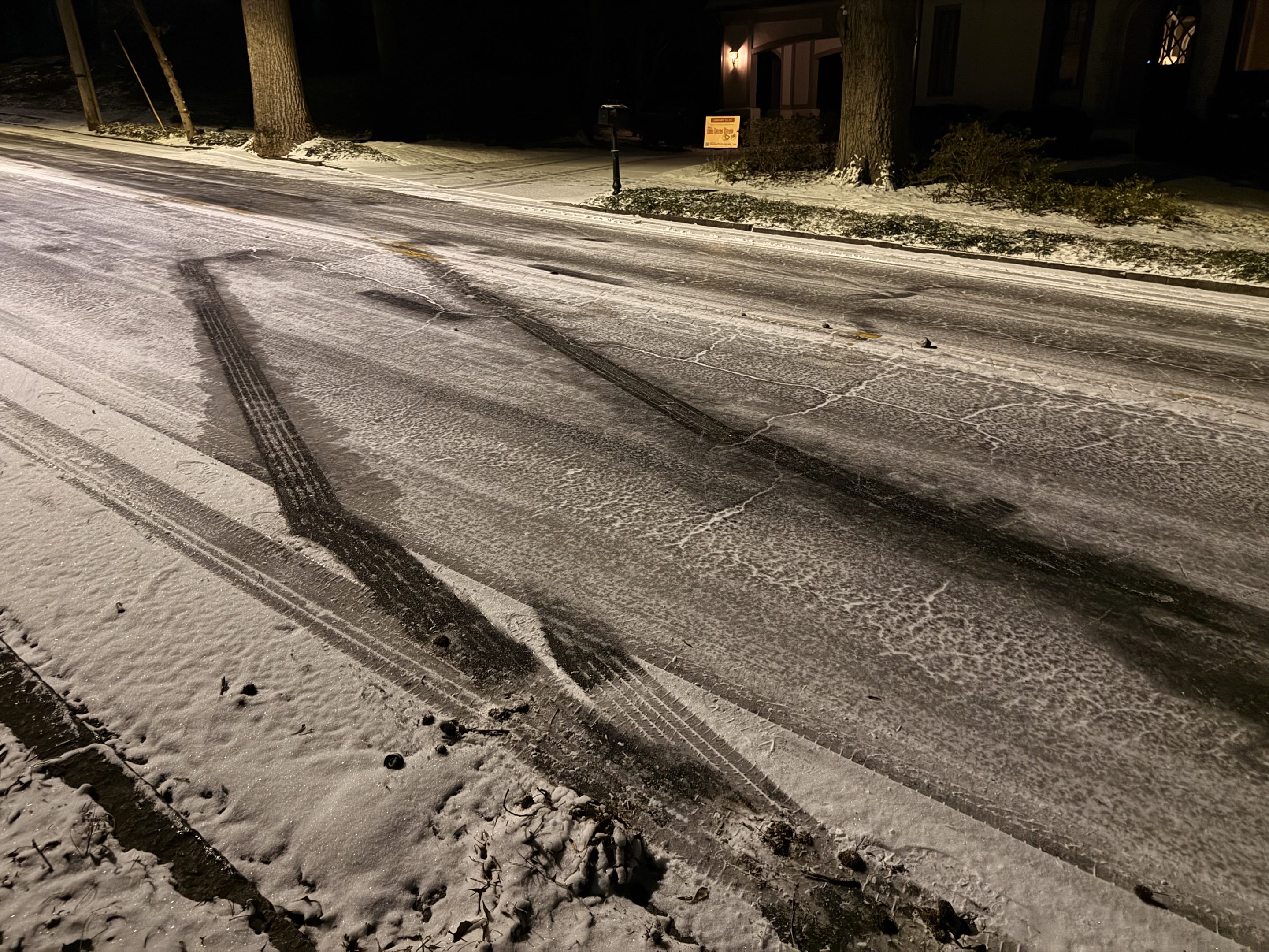 A two-lane road covered with ice with tire skid marks across it
