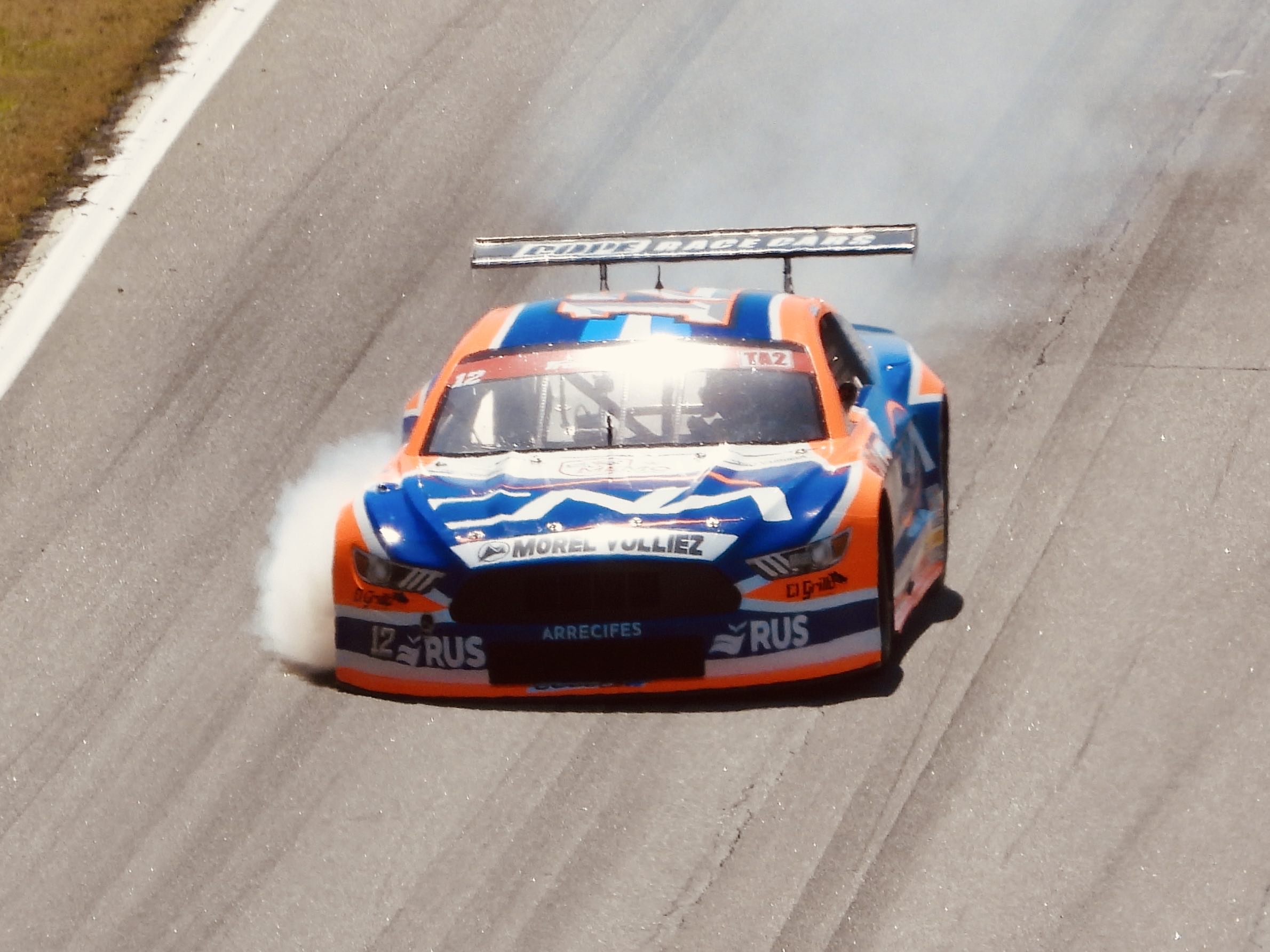 A TA2 car careens downhill with its right front tire billowing smoke
