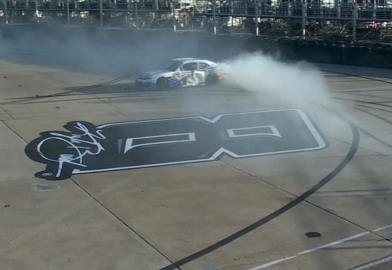 Austin Hill doing a long arcing burnout around the tribute graphic for Kyle Busch at Naval Base Coronado
